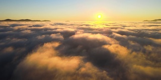 从空中俯瞰，在白色的浓雾中，五颜六色的日出和远处地平线上小山的黑色剪影