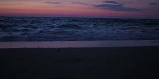 太阳落山后，人们在黄昏时到海里游泳。远处可以看到漂浮的人。在海边度假。日落