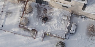 一个成年人在冬天下雪后用铲子清理门廊上的积雪。鸟瞰图直接上方的无人机慢动作视频。