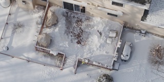 一个成年人在冬天下雪后用铲子清理门廊上的积雪。鸟瞰图直接上方的无人机慢动作视频。