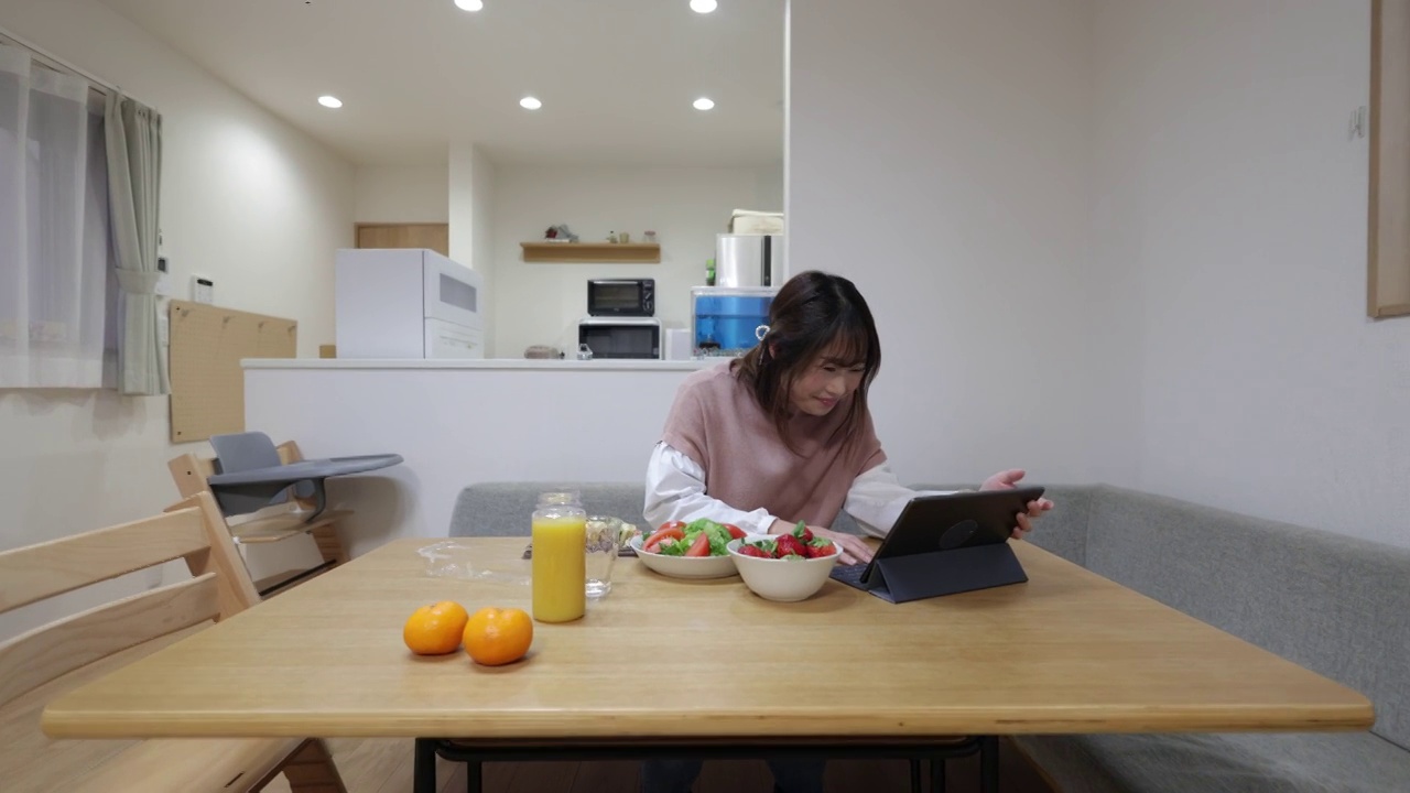 女人在家里用数码平板电脑吃午饭看电影