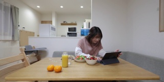 女人在家里用数码平板电脑吃午饭看电影