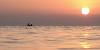 清晨，在橙色的太阳下，渔民们驾着小船出海捕鱼