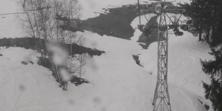 透过窗户，你可以看到从缆车下降到到达站，经过树木和滑雪者在雪道上
