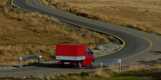 红色的小型货车在有很多弯道的道路上行驶