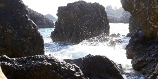 波浪拍打着陡峭的卵石海岸，溅起了水花