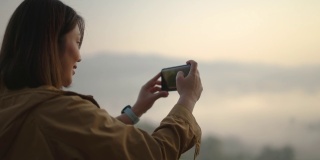 女子在山上放松，用智能手机拍照