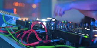 跟踪拍摄的男子DJ玩混音和数字转盘。带有电线、按钮和滑块的CDJ唱盘，由夜总会的电子音乐主持人播放。