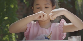 靠近可爱的亚洲小女孩的美丽的脸，坐在户外阳光下玩耍，展示了在家儿童休闲活动的概念，表达快乐，乐趣和快乐的情感。