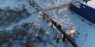 在下雪的院子里，工人在修理车间附近的外管道