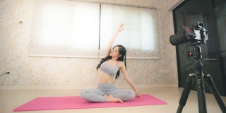 年轻的亚洲妇女教瑜伽在线或现场直播在家里为健康或健康的生活方式概念。