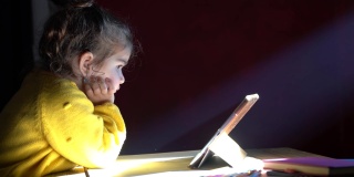 学龄前女孩在光束下使用数码平板电脑的4K视频