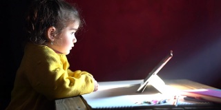 学龄前女孩在光束下使用数码平板电脑的高清视频