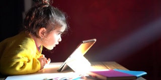 学龄前女孩在光束下使用数码平板电脑的高清视频