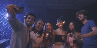 各种各样的年轻人在生日派对上跳舞，用智能手机自拍