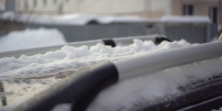 一名男子用刷子清理车顶上的积雪。汽车被雪覆盖着。天气灾害。4 k