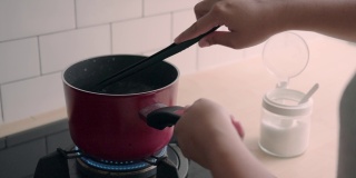 一个女人在厨房里做饭，在锅里搅拌酱汁