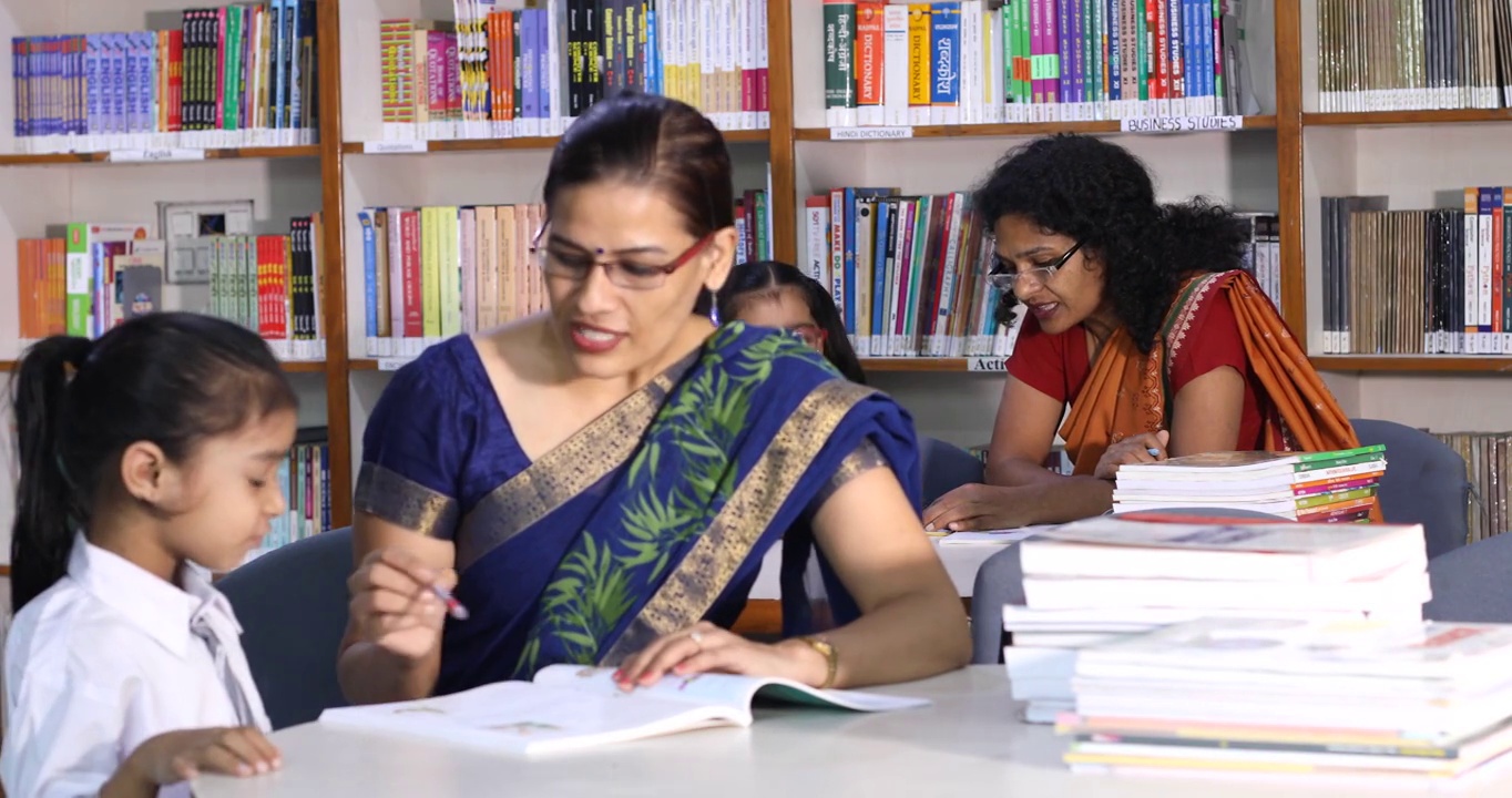 在图书馆帮助女学生学习的老师