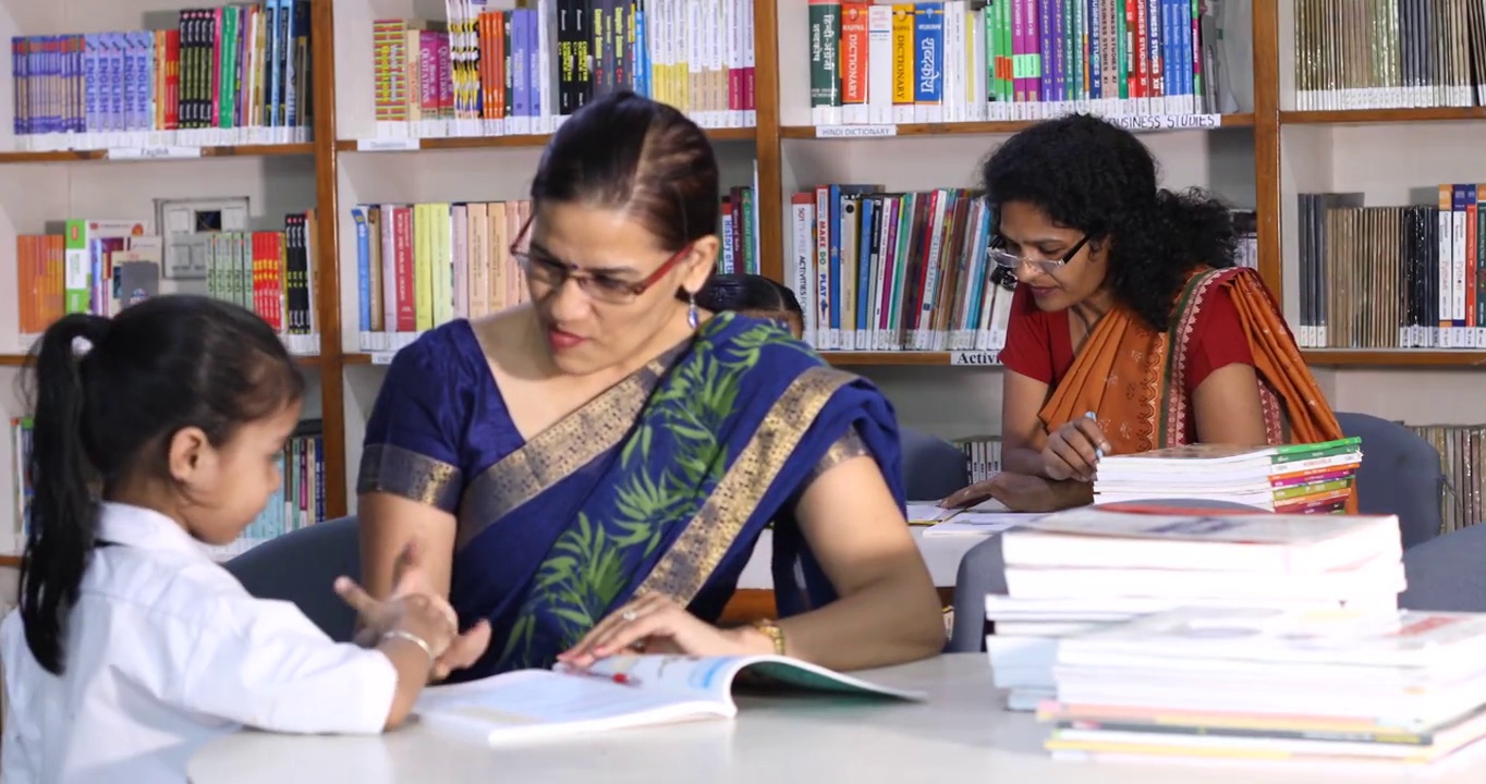 在图书馆帮助女学生学习的老师