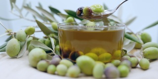 丰富的季节收获的橄榄水果，勺子成熟的橄榄水果和滴橄榄油在慢动作，有机橄榄油生产