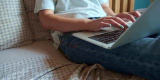 年轻女子用笔记本电脑快速敲击键盘工作，躺在卧室的床上，灵活的工作时间和远程工作。