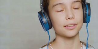 一个戴着蓝色耳机的少女听着平静的音乐的特写镜头