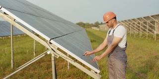 专业的能源技术员在户外站测量太阳能电池的电压。穿着制服和头盔的印度人用万用表进行服务工作。测量太阳能电池的电压