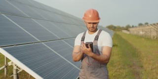 印度工人穿着制服，戴着安全帽和眼镜，用万用表检查太阳能电池板的工作。以人为本，以维护为本，以绿色能源为本。工程师检查太阳能电池板的电阻