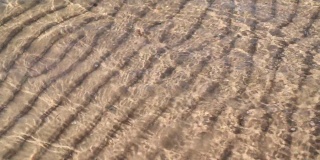 海洋光波和沙底纹理。水中的涟漪