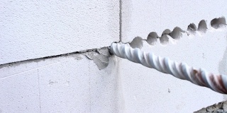 建筑工人用穿孔器在墙上钻一个洞