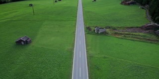 奥地利阿尔卑斯村庄绿色田野之间的道路，鸟瞰图