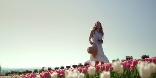 快乐的女孩在郁金香花园里转身。有创意的年轻女子欣赏鲜花