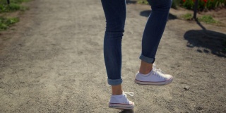 特写女人的腿走在运动鞋。穿着白色运动鞋的无名女孩。