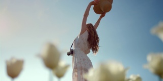 一个戴着太阳帽的无名女子，在阳光明媚的日子里把手伸向蓝天。