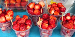水果市场上盛着新鲜红草莓的塑料杯。当地的农民市场