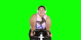 胖女人戴着耳机骑健身自行车