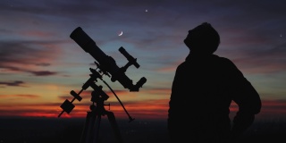 一个人的剪影，望远镜和星空下的乡村