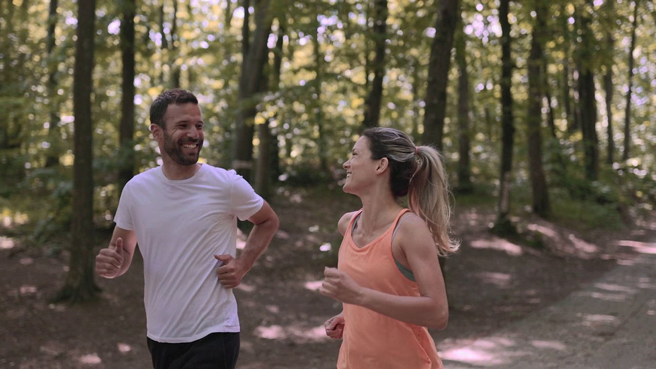 快乐的运动情侣一边在大自然中跑步一边聊天。