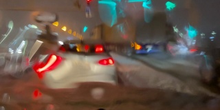 潮湿的道路，特写镜头，汽车行驶在夜晚的冬季街道上。雨雪落在汽车的挡风玻璃上。在恶劣天气，车辆行驶在潮湿、多雨、湿滑的道路上