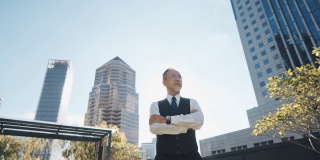 亚洲中国公司首席执行官双臂交叉站在城市办公楼的屋顶上，上午望向别处