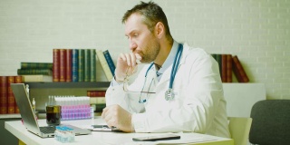 一位中年医生坐在诊所里思考一份研究报告