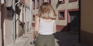 年轻女子在老街里奔跑，看着镜头