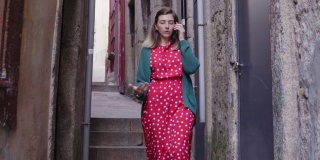 《漂亮女人的旅行者》在狭窄的街道上行走，用手机聊天