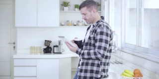 一个白人男人在用平板电脑和喝咖啡