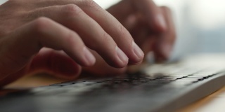 手年轻的商人忙于工作的电脑键盘微缩镜头。近距离男子坐在家庭办公室的桌子和工作与PC软件应用技术在线。用键盘打字的人