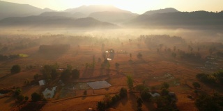鸟瞰村庄和农村贫瘠的土地在日出，背景山。