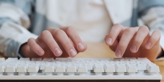 年轻男子学生在家里用电脑打字，关上。Guy Hands Hands在电脑上快速编写文档。个人工作办公室在桌面键盘。工人客户支持时间间隔