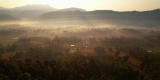 鸟瞰村庄和农村贫瘠的土地在日出，背景山。