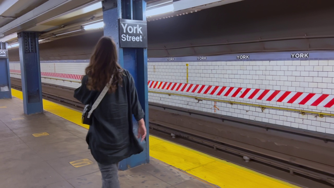 一名戴着防护口罩的妇女走在纽约地铁站台上