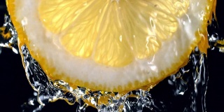 柠檬片(背光)从顶部的水溅到慢动作